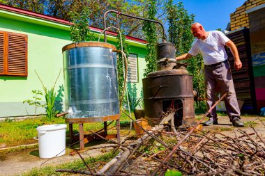 Adam manuel olarak el ile bakırdan yapılmış el yapımı içki imalathanesinde meyve markı karıştırmak, kaçak içki, brendi, konyak, viski, viski, viski, viski, cin, viski gibi alkollü içecekler yapmak için kolu çeviriyor..