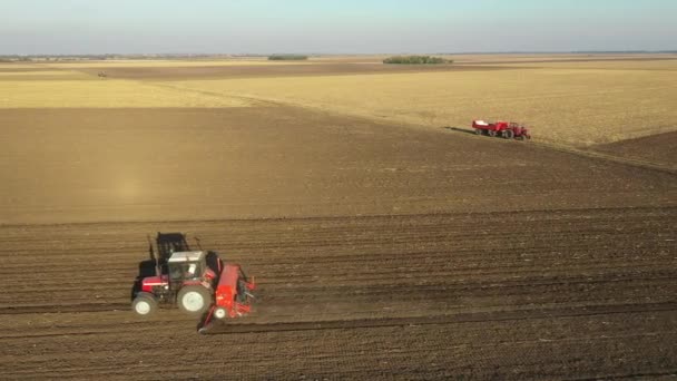 耕作可能なフィールド 新しい小麦作物を植える上に種子ドリルマシンを引っ張るトラクターのドーリー移動ショット — ストック動画