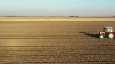 Çekicinin yan tarafındaki çekimde tohum makinesini tarlaya, toprağa, yeni buğday ekimine çekiyorlar..