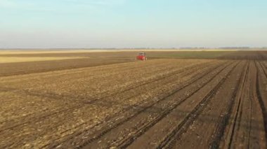 Çekicinin tepesinde, tohum makinesini tarla, toprak ve yeni buğday ekimi üzerine çekerken çekilen çekimin görüntüsü var..