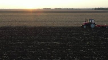 Traktörün yan görüş açısının üstünde, makineyi çekiyor, tarlayı yıpratıyor, toprağı gelecek sezon ekime hazırlıyor..