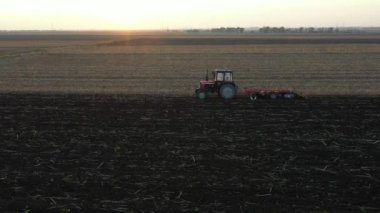 Çekicinin tepesinde bir disk tırabzanı sürüklerken, tarla tarlasını yıpratırken, toprağı yeni ekin ekimi için hazırlarken....