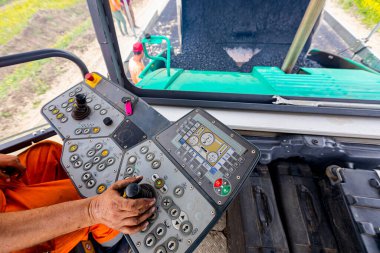 İşçi, joystick işletim gidon, asfalt yol Döşeme makinesi operatörü kontrol ediyor.