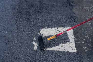 İşçi bir fırça rulosu kullanarak asfaltı kaplıyor, su geçirmezliğinin ilk temel koruyucu katmanını uygula.