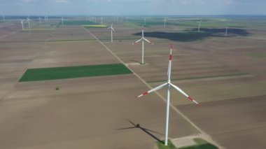 Above view on farm of large wind power turbines are standing among agricultural fields, generating clean renewable electrical energy for sustainable development.
