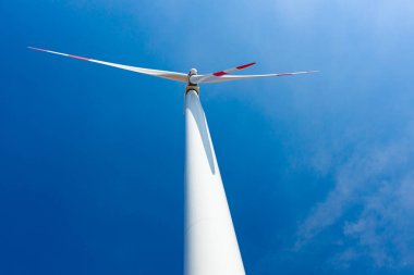 Düşük açı görüşü, rüzgar jeneratörünün altında türbinler, dönen bıçaklar, pervaneler, mavi gökyüzüne karşı yenilenebilir temiz enerji kinetik enerjiyi dönüştürüyor..