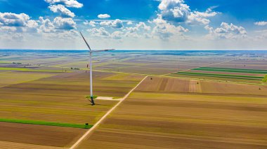 Yüksek rüzgar gücü türbinleri tarımsal alanlar arasında duruyor ve sürdürülebilir kalkınma için temiz yenilenebilir elektrik enerjisi üretiyorlar..