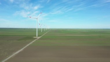 Yukarıda, büyük rüzgar santrallerinin üzerinde tarımsal alanların arasında durarak temiz, yeşil, yenilenebilir elektrik enerjisi üretiliyor..