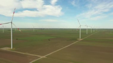 Yukarıda, büyük rüzgar santrallerinin üzerinde tarımsal alanların arasında durarak temiz, yeşil, yenilenebilir elektrik enerjisi üretiliyor..