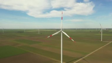 Yukarıda, büyük rüzgar santrallerinin üzerinde tarımsal alanların arasında durarak temiz, yeşil, yenilenebilir elektrik enerjisi üretiliyor..