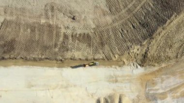 Titreşim plaka sıkıştırıcı temeli kullanarak çalışan sıkıştırma temeline en üstteki görünüm, üstteki görünümün üzerindeki tepedeki kule titreşim plakalı sıkıştırıcı kum, inşaat alanındaki sıkıştırma makinesi olarak işçiye doğru kayar.