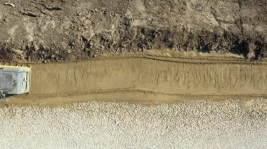 Üst görünümün üzerinde, doli hareket işçisi inşaat alanında kumu titreşim plakası, sıkıştırıcı makine ile sıkıştırıyor.