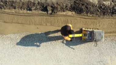 Üst görünümün üzerinde, doli yukarı hareket eder, takip eder ve yukarı doğru, işçi inşaat alanında titreşim plakası ile kum sıkıştırır, sıkıştırıcı makine.