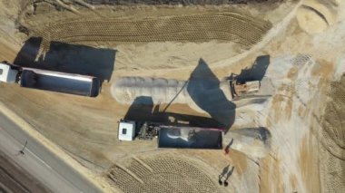 Üst tarafta, kargoyu boşaltmak için karavanını kaldırırken, üst tarafta, buldozer sürüngeninin ittiği, inşaat sahasında düzleştirdiği küçük, ezilmiş taş var..