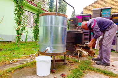 Adam, kaçak içki ve alkollü içecekler yapan ev yapımı bir içki imalathanesinin şömine rafına kuru dallar atıyor..