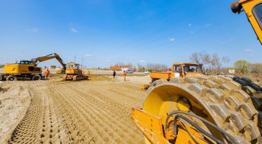 Vibratörlü yol silindirini görüntüle, dikenler titreşiyor, sıkıştırıcı sıkıştırıyor, inşaat alanındaki yol temeli için kumu dolduruyor.