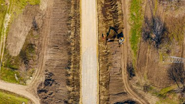 Yeni yolun en üst katında inşaat, temel, kazıcı toprak kazma, yol boyunca arazi düzenleme, işçiler küreklerle sıralanır. 