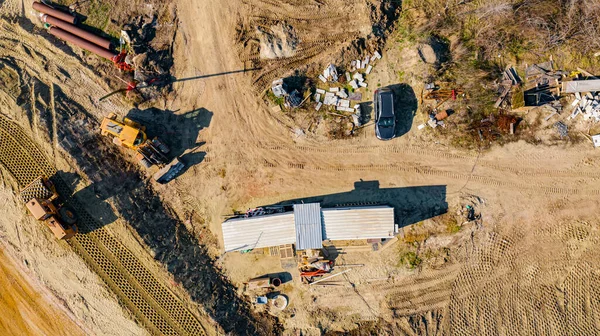 Above top view on the building site with mechanization, roundabout under construction with road that goes over unfinished bridge.