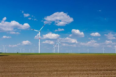 Birkaç büyük rüzgar enerjisi türbininin çiftliği tarım alanlarının arasında duruyor ve temiz yenilenebilir elektrik enerjisi üretiyorlar.