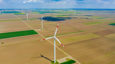 Yüksek rüzgar gücü türbinleri tarımsal alanlar arasında duruyor ve sürdürülebilir kalkınma için temiz yenilenebilir elektrik enerjisi üretiyorlar..