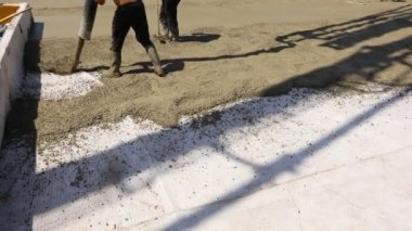 Construction worker is directing the pump tube on right direction, pouring first layer of concrete in building foundation.