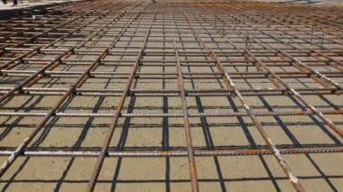Low angle view, perspective, on flow fresh liquid concrete is slowly under square reinforcement in the base of new building.