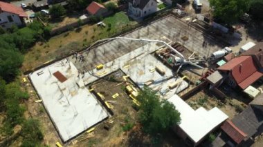Aerial view construction site, mixer truck pouring concrete into pump machine pumping to exit tube, worker is directing the on right direction, building foundation. Riggers, workers leveling concrete