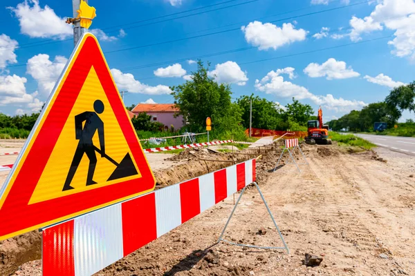 Work in progress, triangle sign with boundary, caution symbol, trench is on construction site.