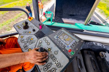 İşçi, joystick işletim gidon, asfalt yol Döşeme makinesi operatörü kontrol ediyor.