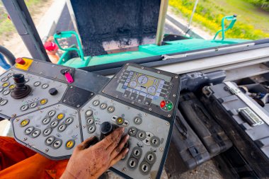 İşçi, joystick işletim gidon, asfalt yol Döşeme makinesi operatörü kontrol ediyor.