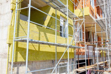Applying thermal isolation stone wool on the brick wall of residential building under construction. Heat insulation with mineral wool.
