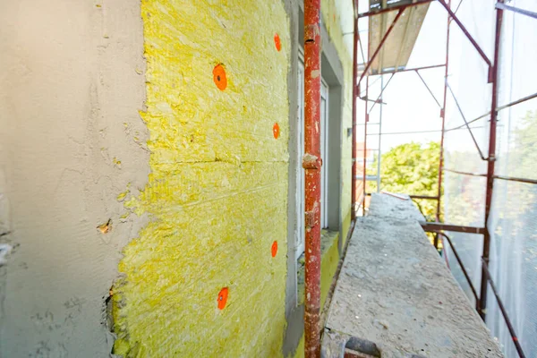 Applied thermal isolation stone wool on the brick wall of residential building under construction, heat isolation with mineral wool.