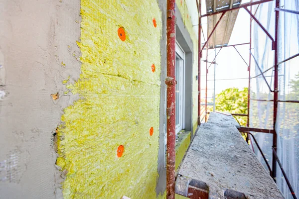 Applied thermal isolation stone wool on the brick wall of residential building under construction, heat isolation with mineral wool.