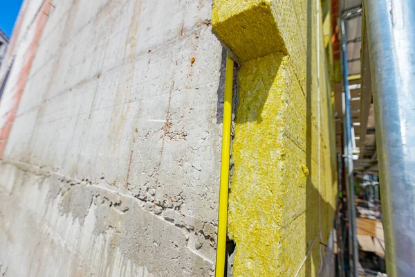 Applying thermal isolation stone wool on the brick wall of residential building under construction. Heat insulation with mineral wool.