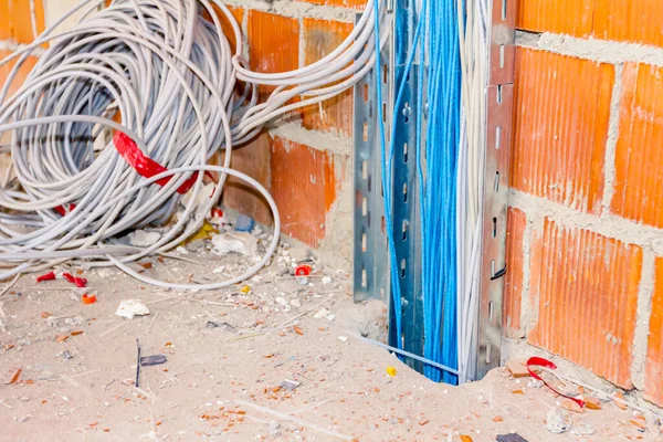 断熱ケーブルの束を有する金属製の穿孔トレイは 建設中の建物内の床二次穴を通って床の間を通過します — ストック写真