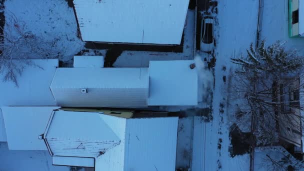 雪に覆われた郊外の集落の空中トップビュー 低温での外観 夕方の家の屋根の上のビュー 雪の白 冬に煙突から出て燃焼の煙 — ストック動画