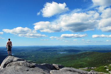 Atlethic young man stands on top of Mount Monadnock enjoying view clipart