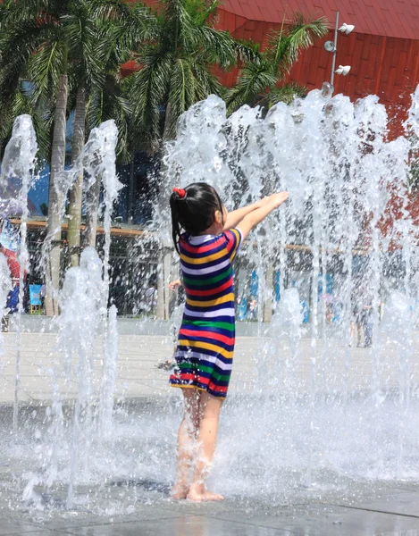 Una ragazza asiatica spruzzata dalla fontana d'acqua in estate — Foto Stock