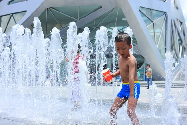 Азиатский ребенок, забрызганный фонтаном летом — стоковое фото