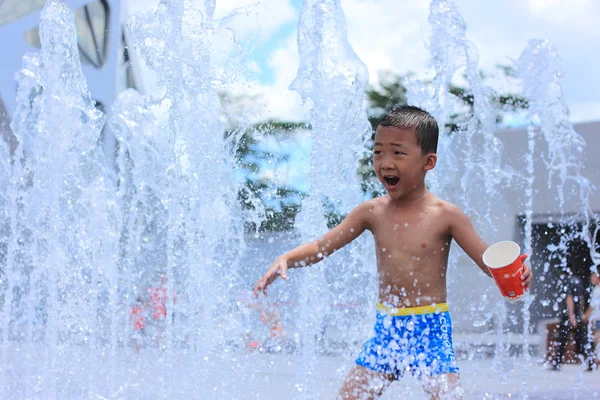 Een Aziatische jongen bespat door Waterfontein in de zomer — Stockfoto