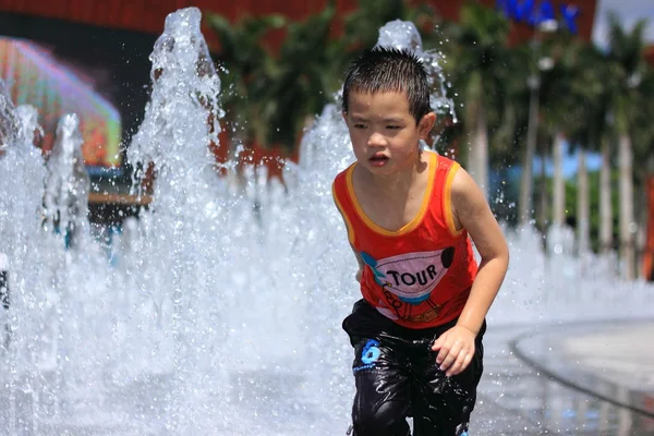 Un bambino asiatico spruzzato da fontana d'acqua in estate — Foto Stock