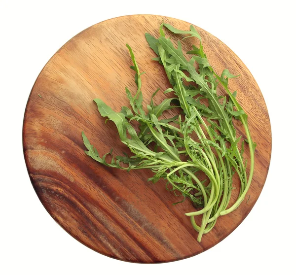 Fresh Rucola on a round wooden board — Stock Photo, Image