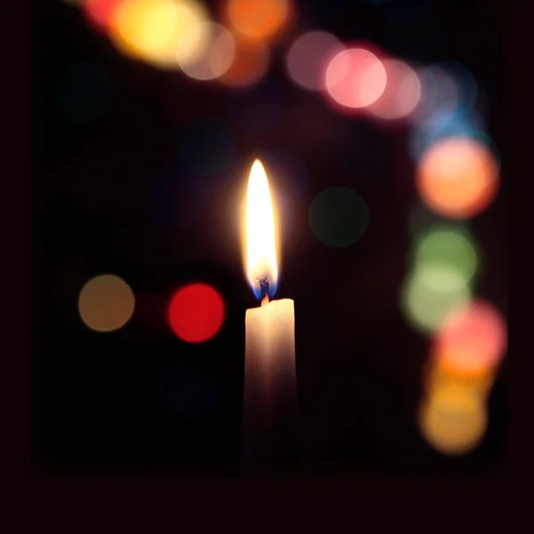 Flame of a candle on a dark background with colored bokeh — Stock Photo, Image