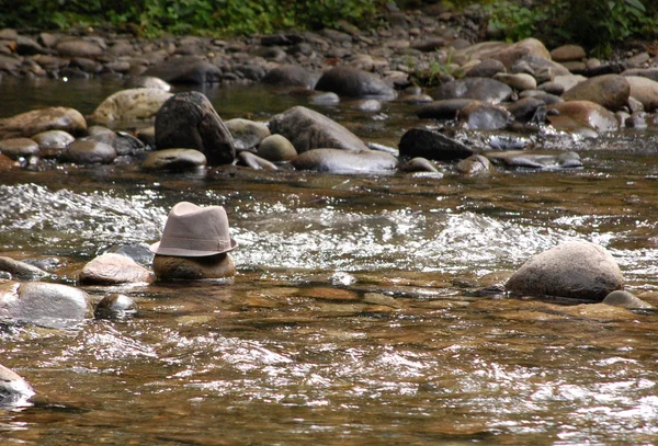 Derby hat on rock in river — Stock Photo, Image