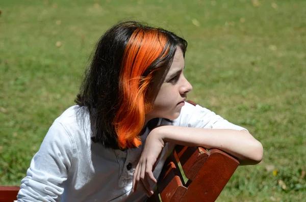 Boy sitting on bench in grass looking right — Stock Photo, Image