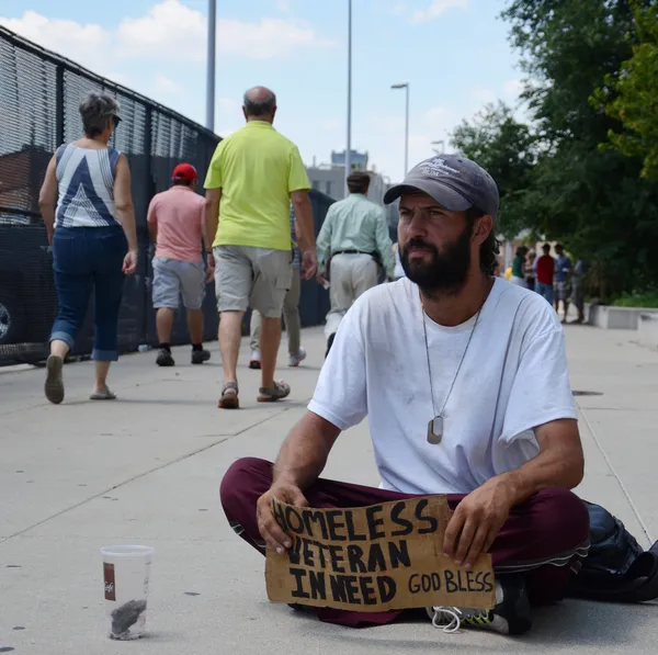 Mensen lopen voorbij daklozen veteraan Rechtenvrije Stockafbeeldingen