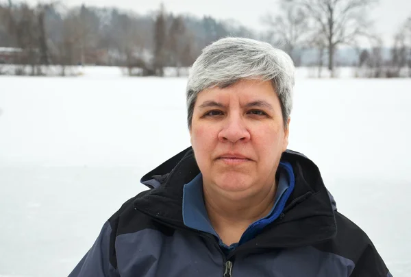 Frau mittleren Alters blickt in die Kamera, Winterhintergrund — Stockfoto