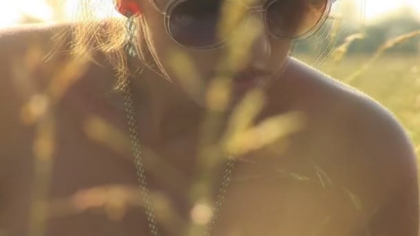 Женщина в белом на зеленом лугу в солнечных очках — стоковое видео