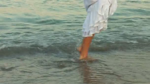 Mujer vestida de blanco caminando sobre las olas — Vídeos de Stock