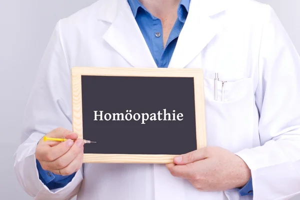 Médico mostra informações sobre quadro-negro: homeopatia — Fotografia de Stock